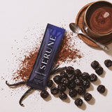 A Serune sachet with cacao powder, dried cherries, vanilla pods and a mug of hot chocolate