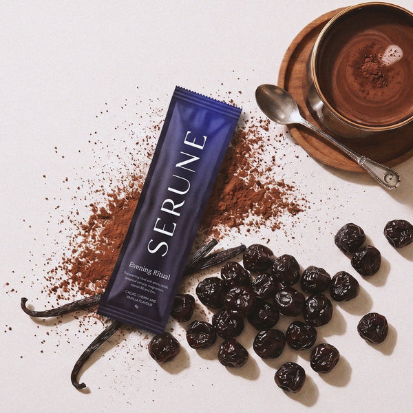A Serune sachet with cacao powder, dried cherries, vanilla pods and a mug of hot chocolate