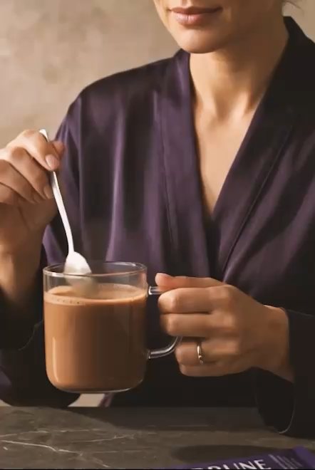 Someone in a purple robe stirring a glass mug of Serune hot chocolate