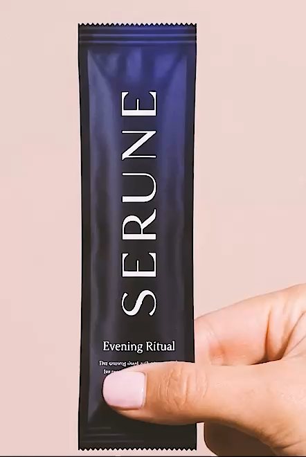 A hand holding a Serune Evening Ritual sachet against a pale pink background